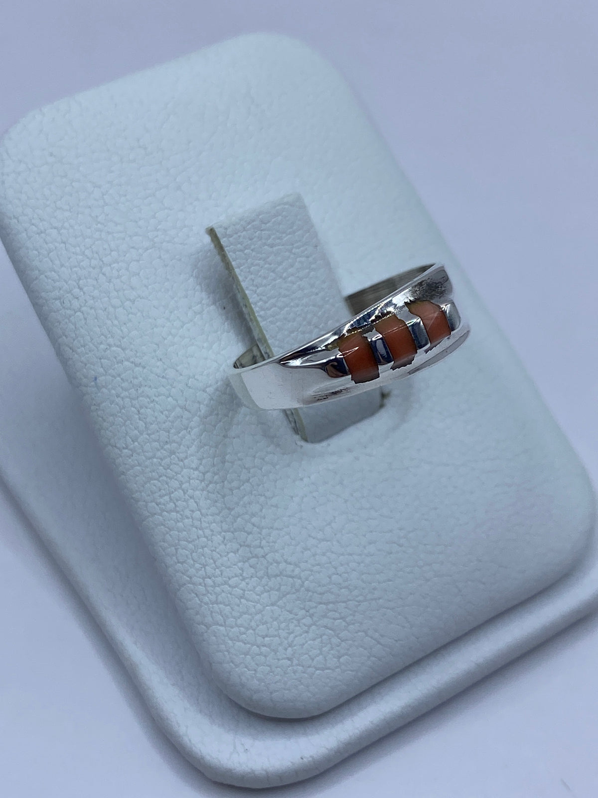 Vista lateral del anillo de plata con coral, mostrando el engaste a mano