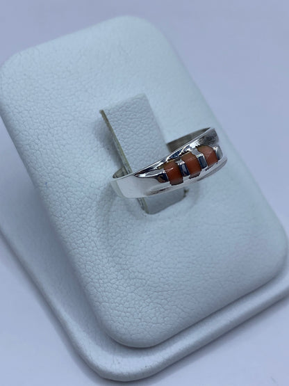 Vista lateral del anillo de plata con coral, mostrando el engaste a mano