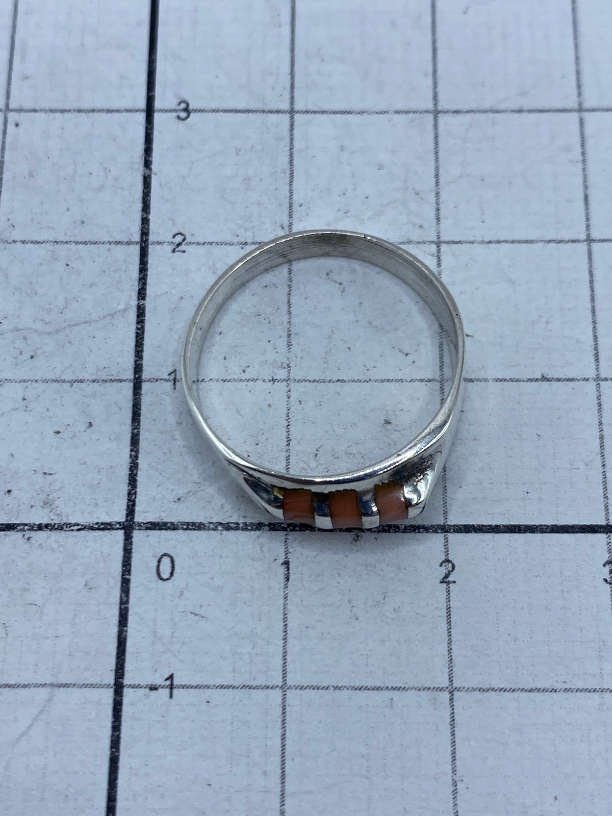 Detalle del anillo sobre una regla métrica, mostrando el acabado pulido de la plata