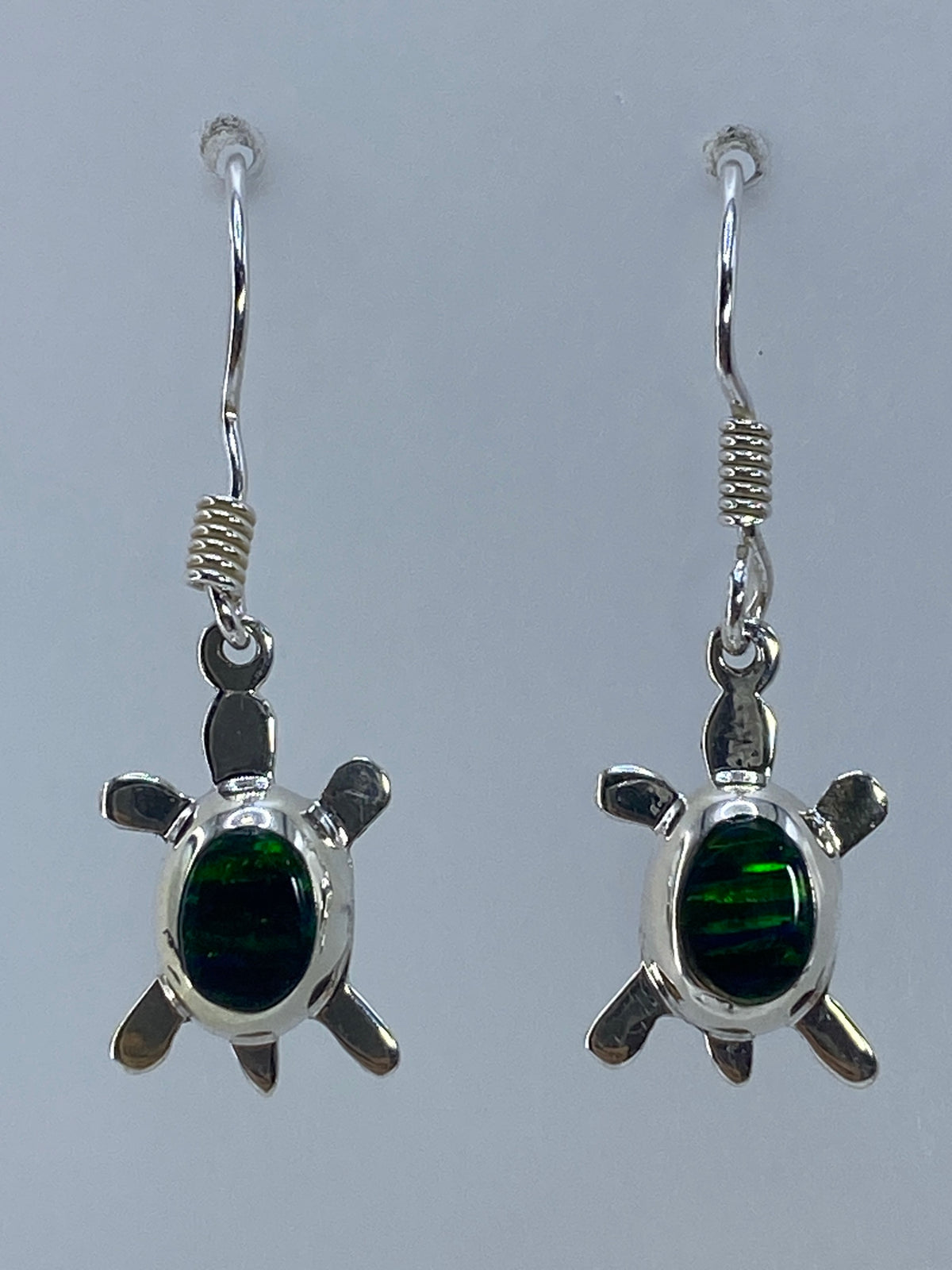 Par de aretes de plata con ópalo de fuego verde, forma de tortuga, sobre fondo gris