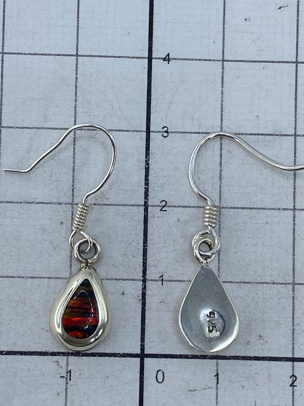 Par de aretes con ópalo multicolor iluminado mostrando reflejos rojos y naranjas