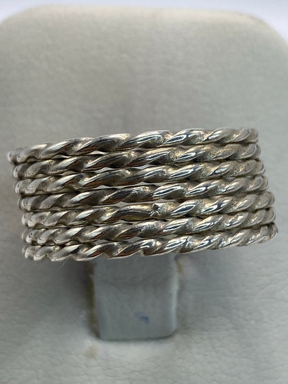 Anillo de plata trenzada puesto en la mano, luz natural reflejada en el trenzado