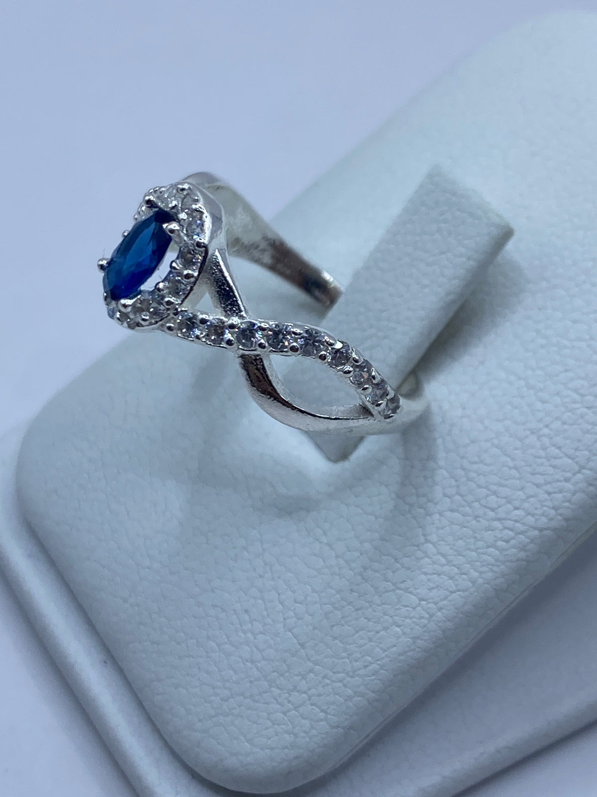 Anillo de plata puesto en dedo de mujer, con la circonia azul brillando bajo la luz