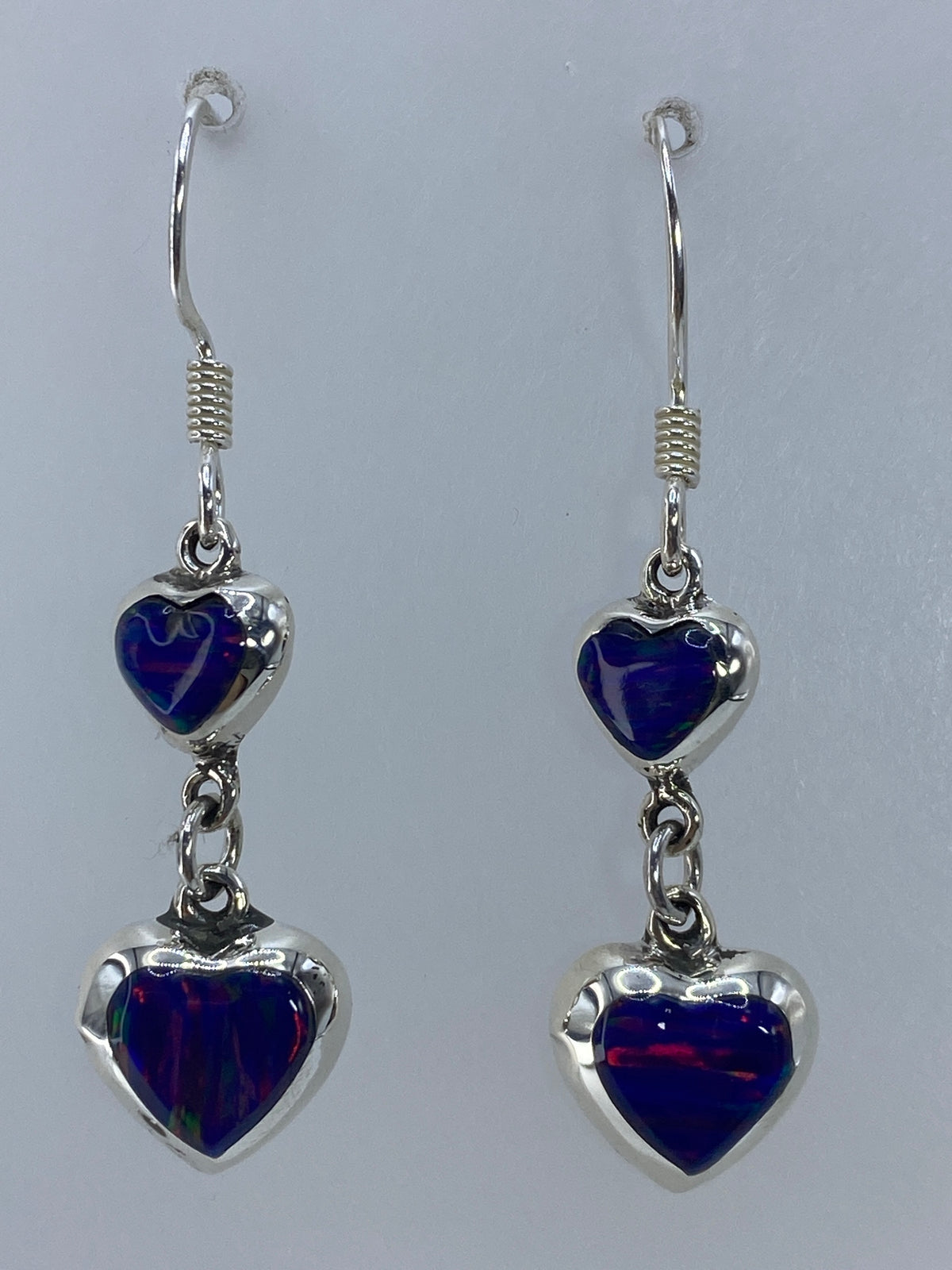 Par de aretes de plata con ópalo de fuego multicolor, vista frontal mostrando bandas de rojo y naranja