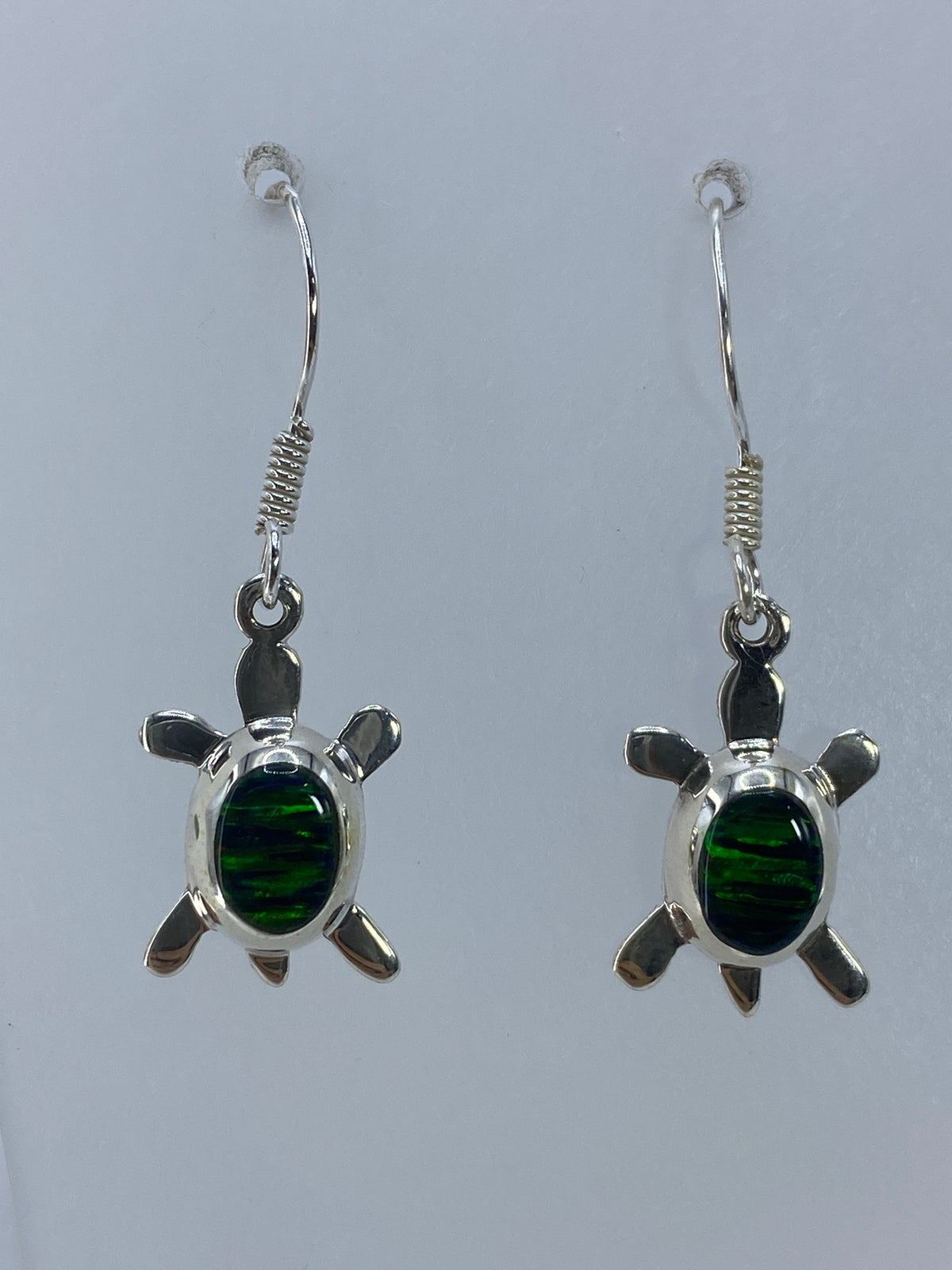 Detalle del ópalo de fuego verde engastado a mano en aretes de plata 925