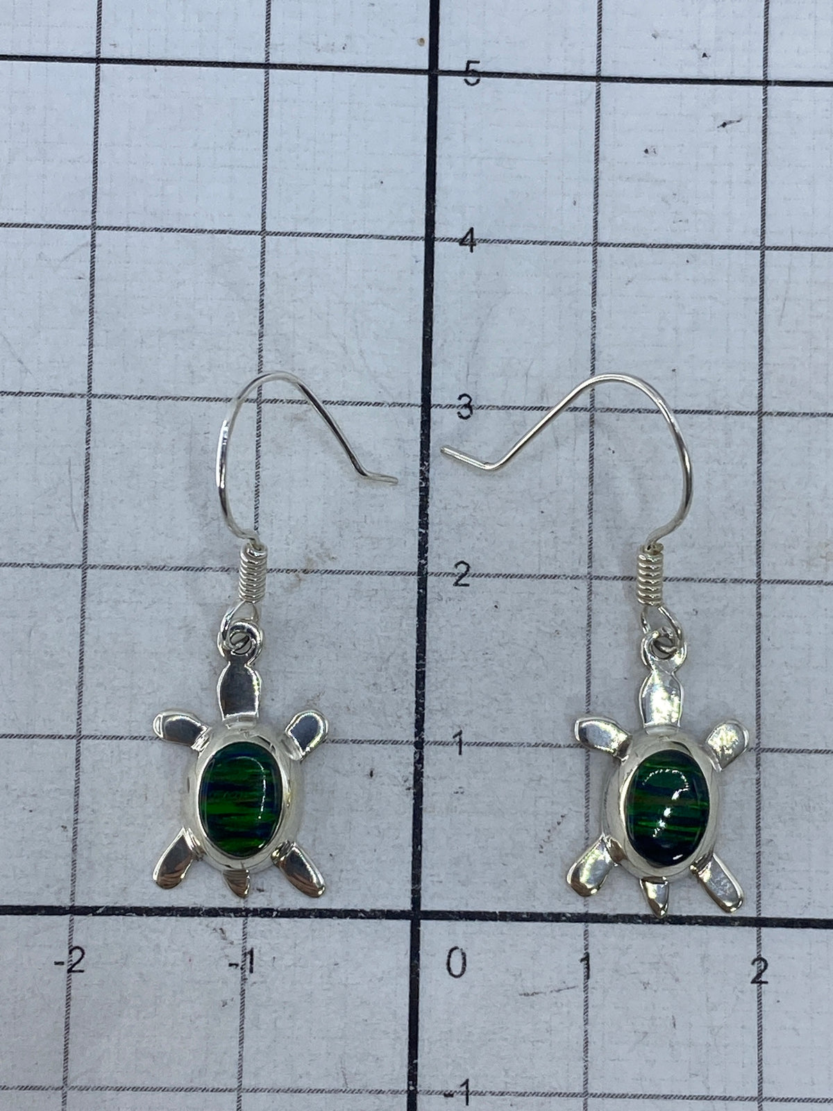 Aretes con ópalo de fuego verde y Quinto 925 visible en la plata