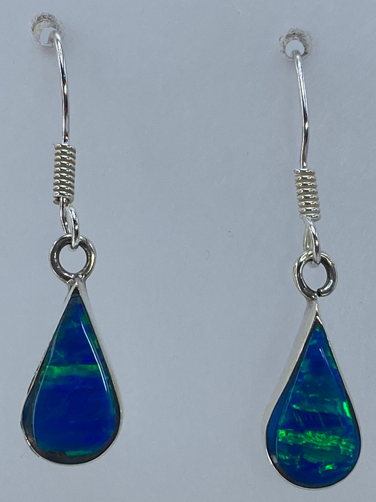 Aretes colgando mostrando el verde olivo y destellos del opalo de fuego