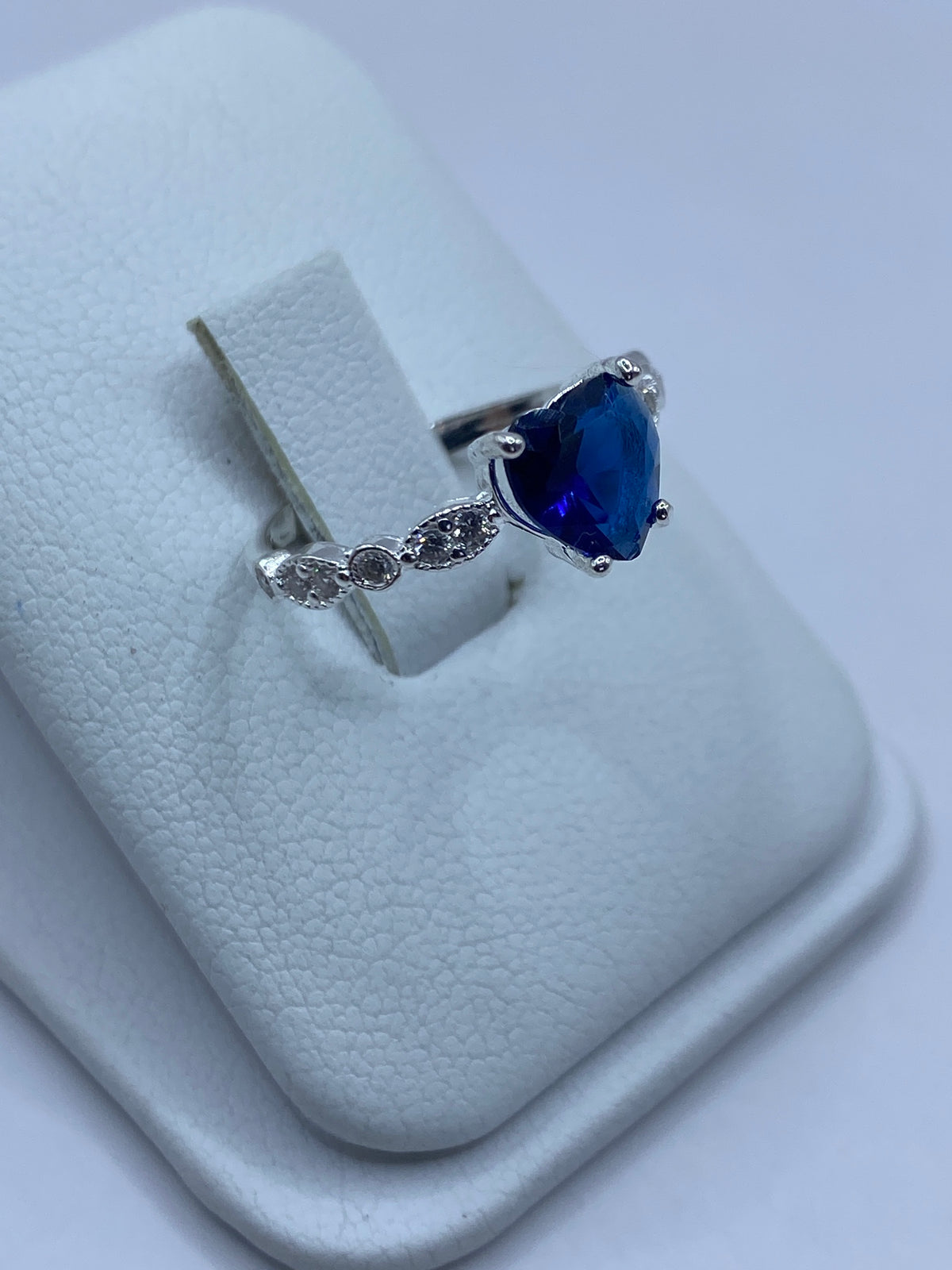 Detalle lateral del anillo mostrando el engaste de piedras y la voluta de micro-circonia