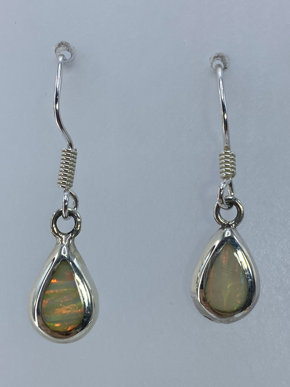 Ópalo de fuego multicolor en aretes de plata 950, detalle de los reflejos anaranjados y verdes