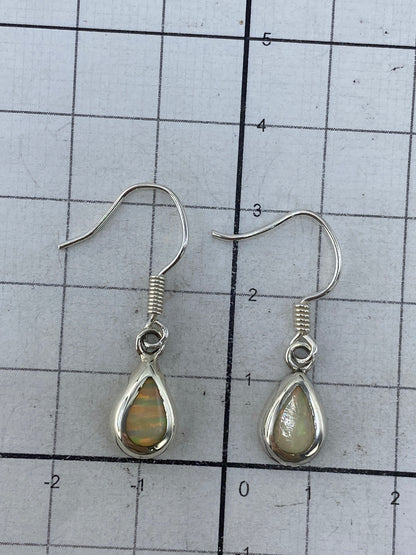 Aretes de plata pura colgando, mostrando el largo de 3 cm y el engaste a mano del ópalo
