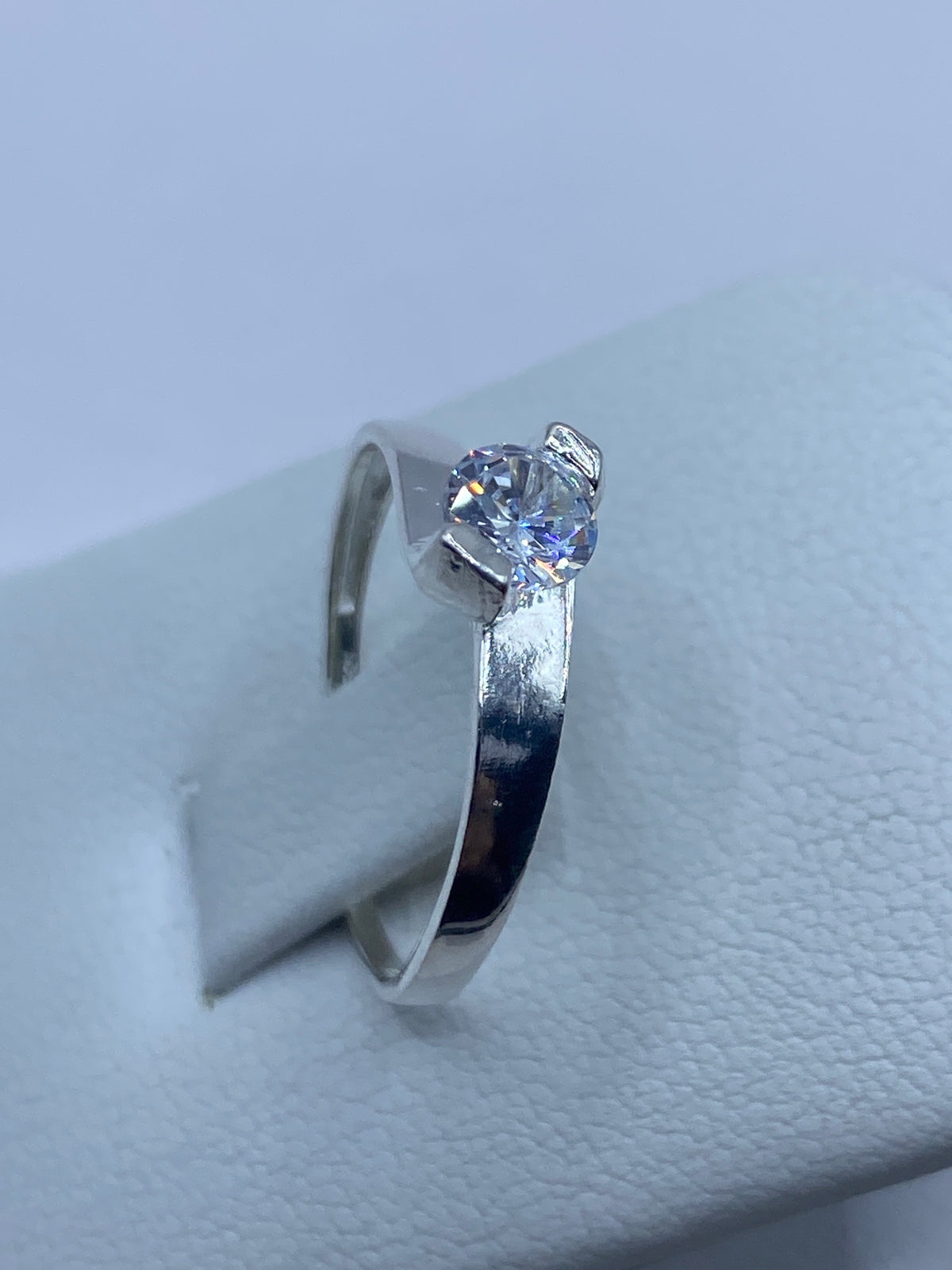 Anillo solitario de plata 925 puesto en un dedo — destello de la circonia