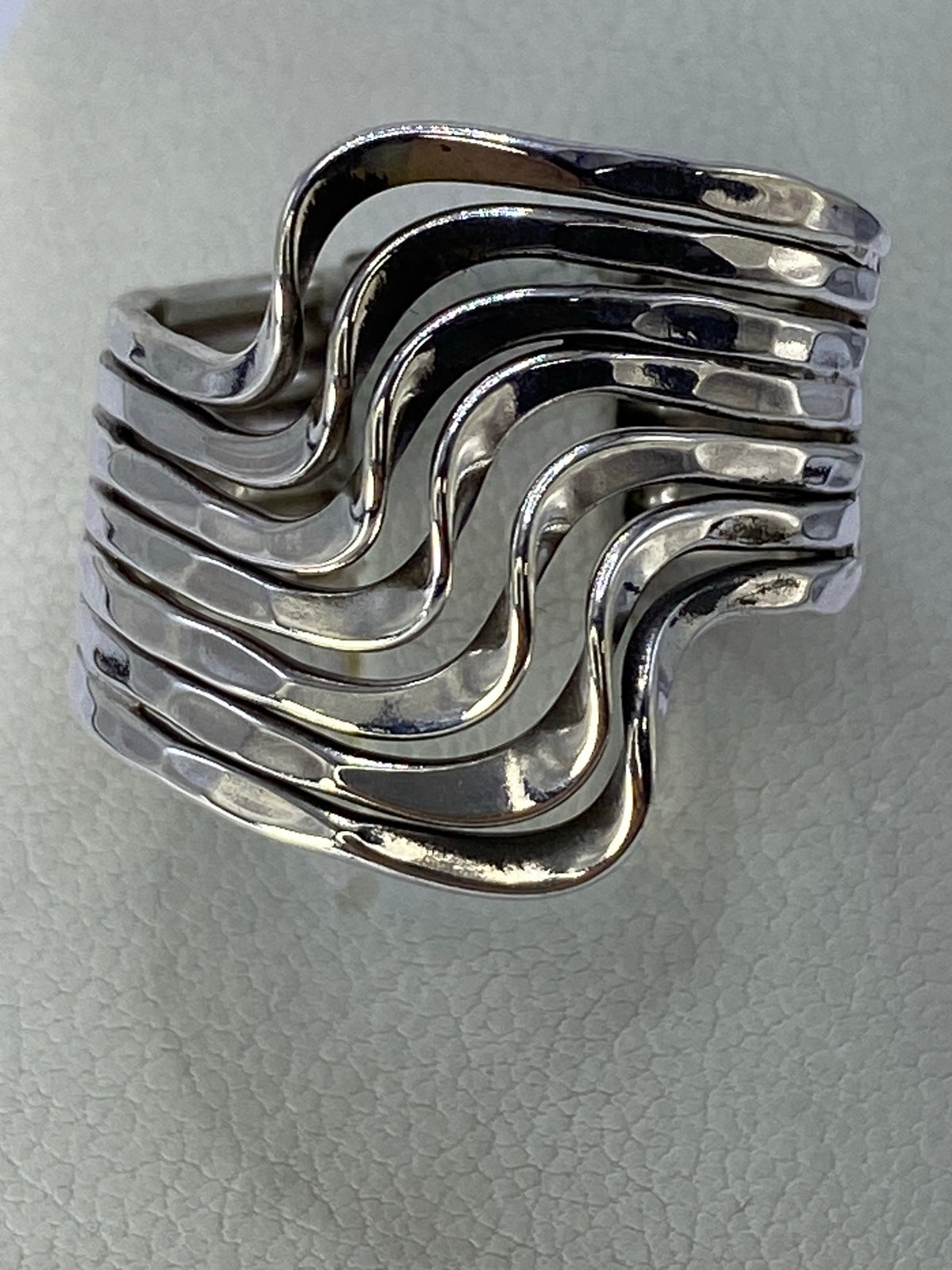 Anillo de plata cartoneado en capas fluidas en mano de mujer