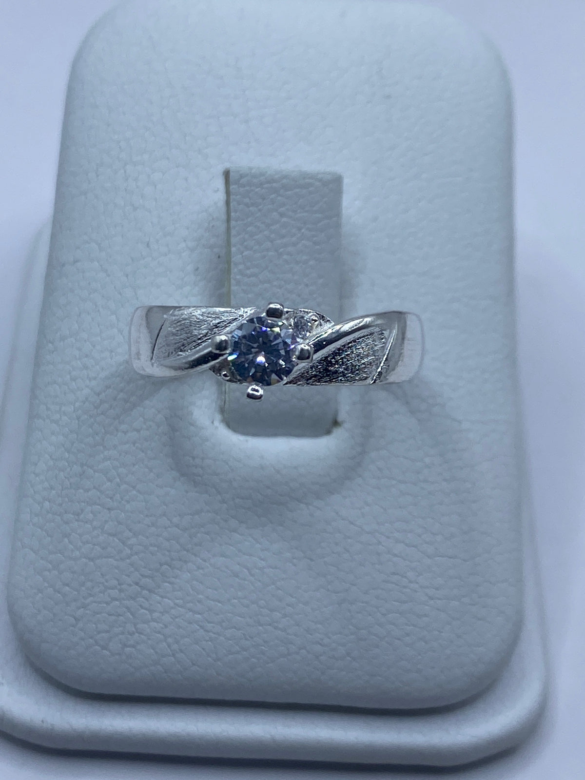 Anillo de plata solitario con circonia blanca brillante en mano de mujer