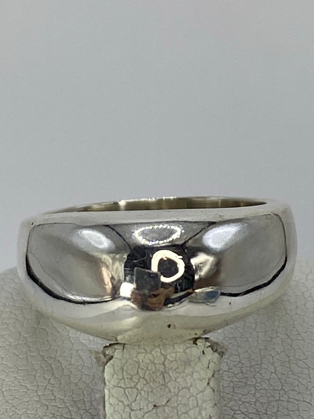 Anillo de plata cartoneado pulido en la mano de una mujer, reflejo brillante