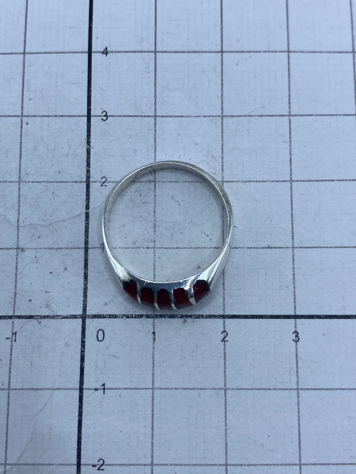 Anillo puesto en mano mostrando el color rojo profundo del coral contra la piel