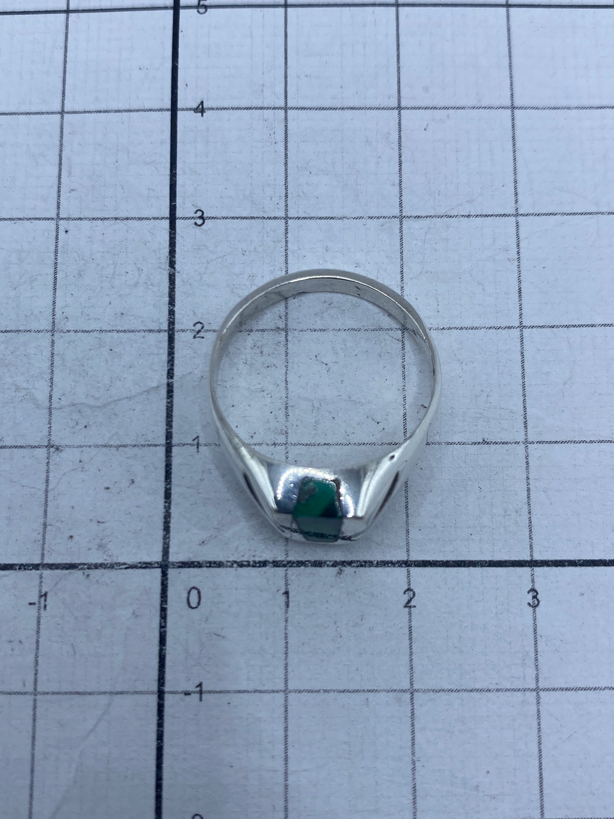 Anillo sobre fondo blanco destacando el color verde profundo de la piedra