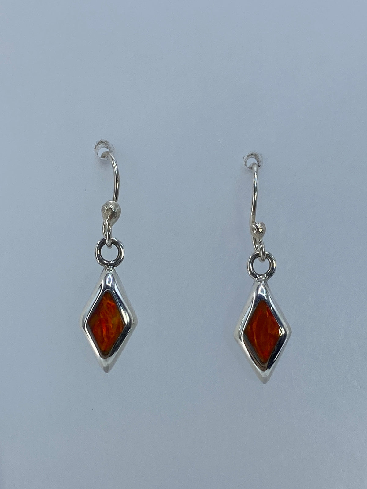 Detalle del arete de plata mostrando el engaste a mano del ópalo de fuego naranja