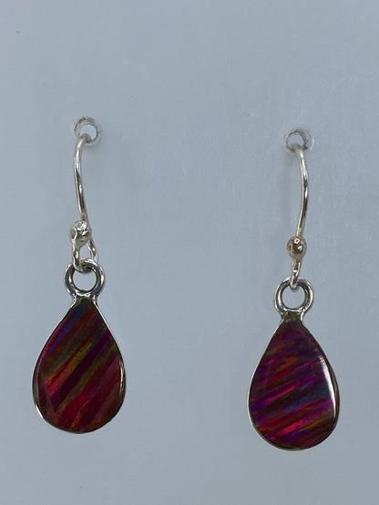 Aretes de plata con ópalo de fuego multicolor colgando, destellos rojos, naranjas y verdes