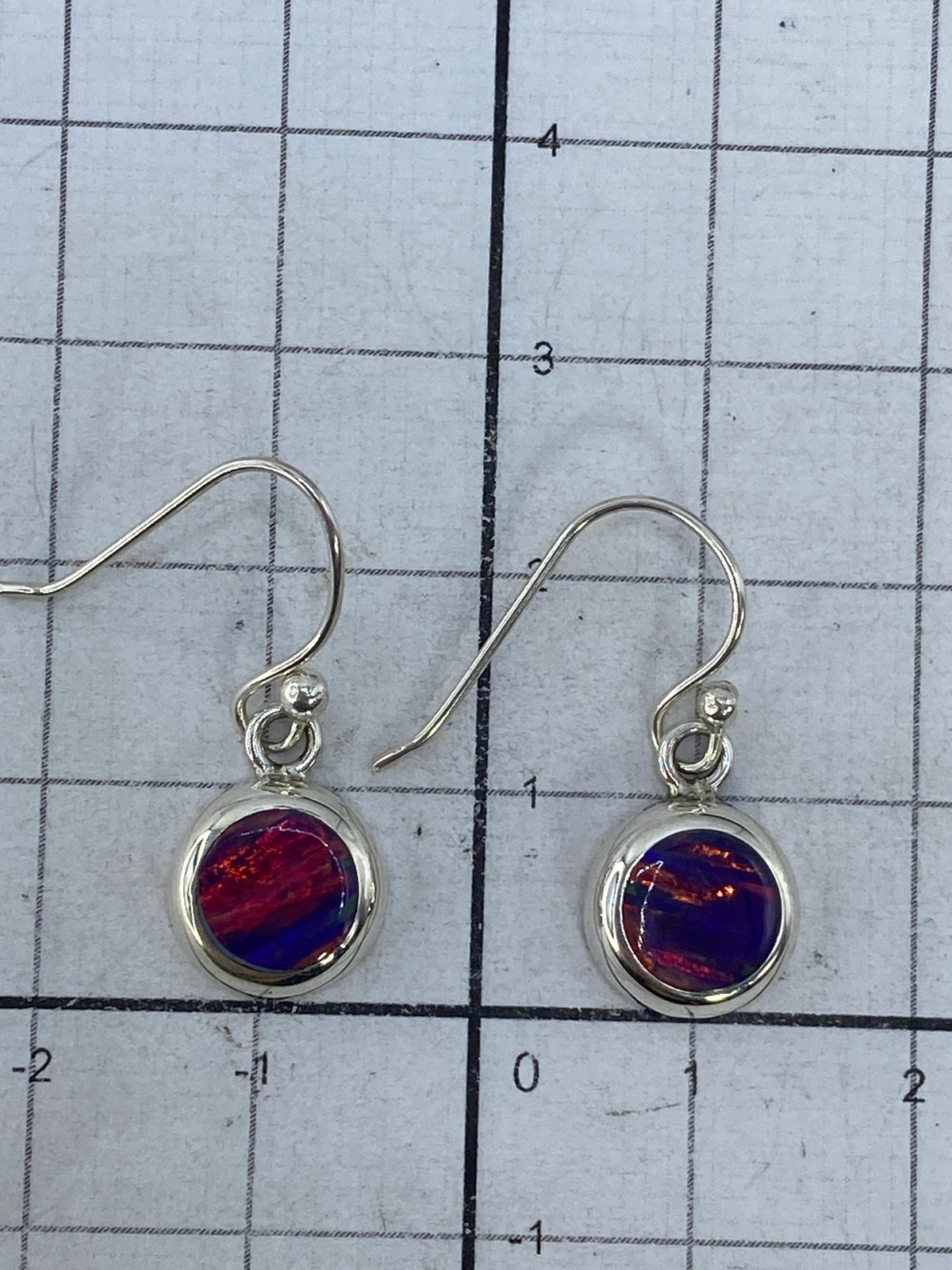 Aretes junto a arete de plata con grabado y texto MEX, comparación de estilos