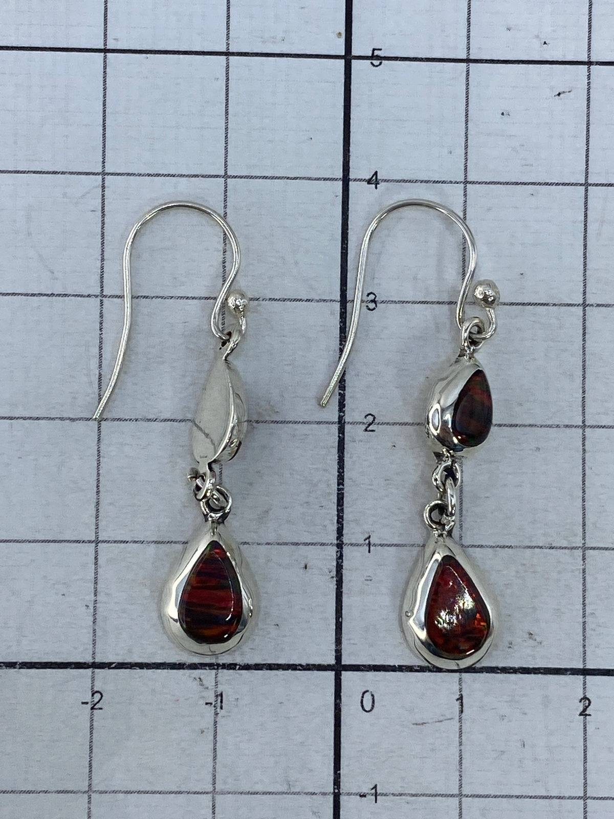 Aretes puestos, largo 3.9 cm, contra fondo claro mostrando la transparencia del ópalo
