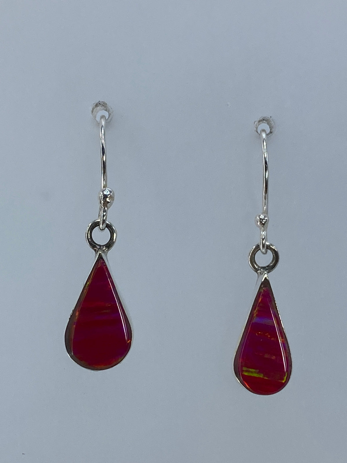 Detalle cercano de un arete mostrando los destellos del ópalo de fuego rosa