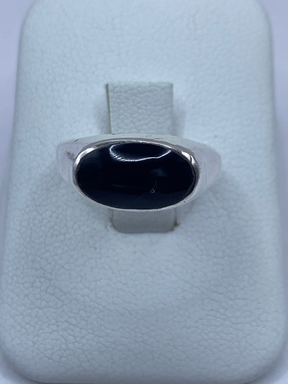 Anillo de plata 950 con ónix negro pulido en mano de hombre