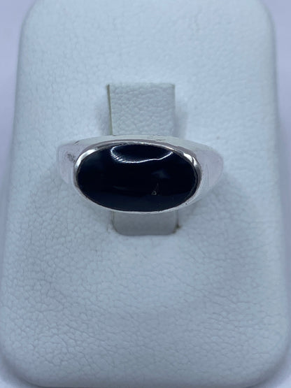 Anillo de plata 950 con ónix negro pulido en mano de hombre