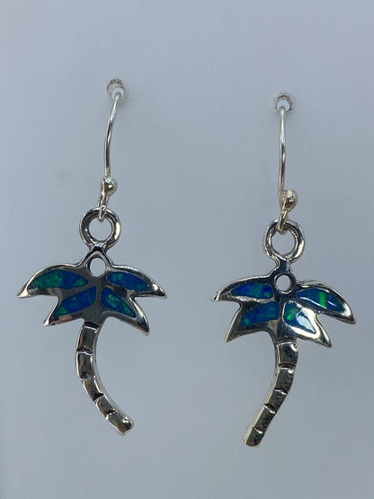 Detalle frontal de un arete: diseño de palmera con ópalo de fuego incrustado brillando en verde olivo