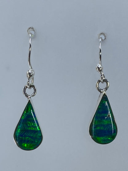 Par de aretes de plata 950 con ópalo de fuego verde engastado, sobre medidor de centímetros mostrando 2.7 cm de largo