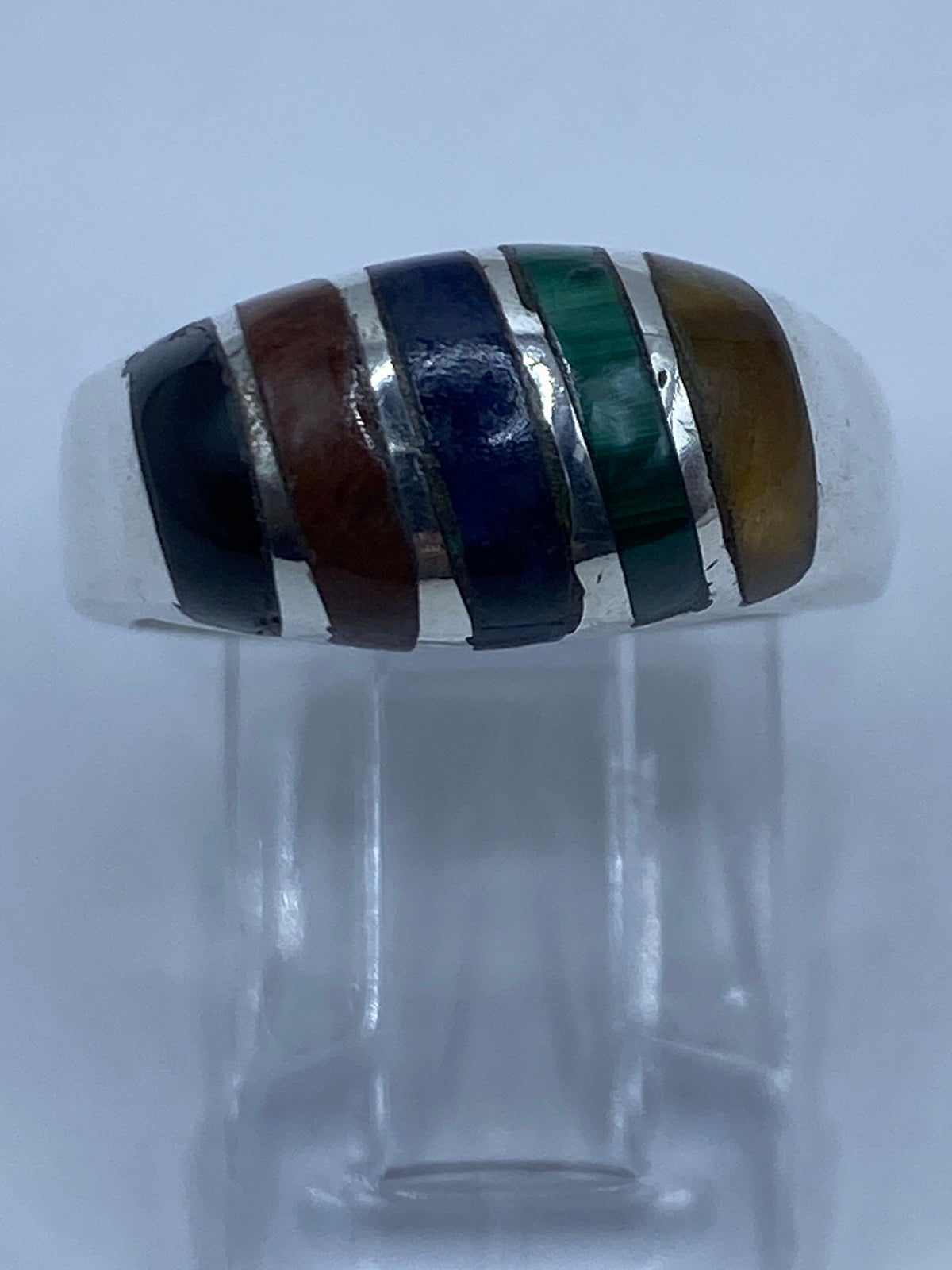 Anillo multicolor llevado en dedo, mostrando el equilibrio de las cuatro piedras
