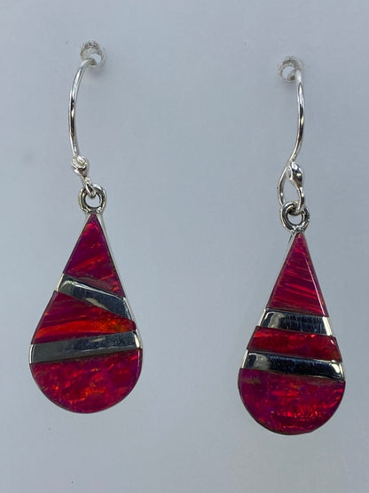 Aretes de plata con ópalo de fuego rosa, largo 3 cm, colgando sobre fondo blanco