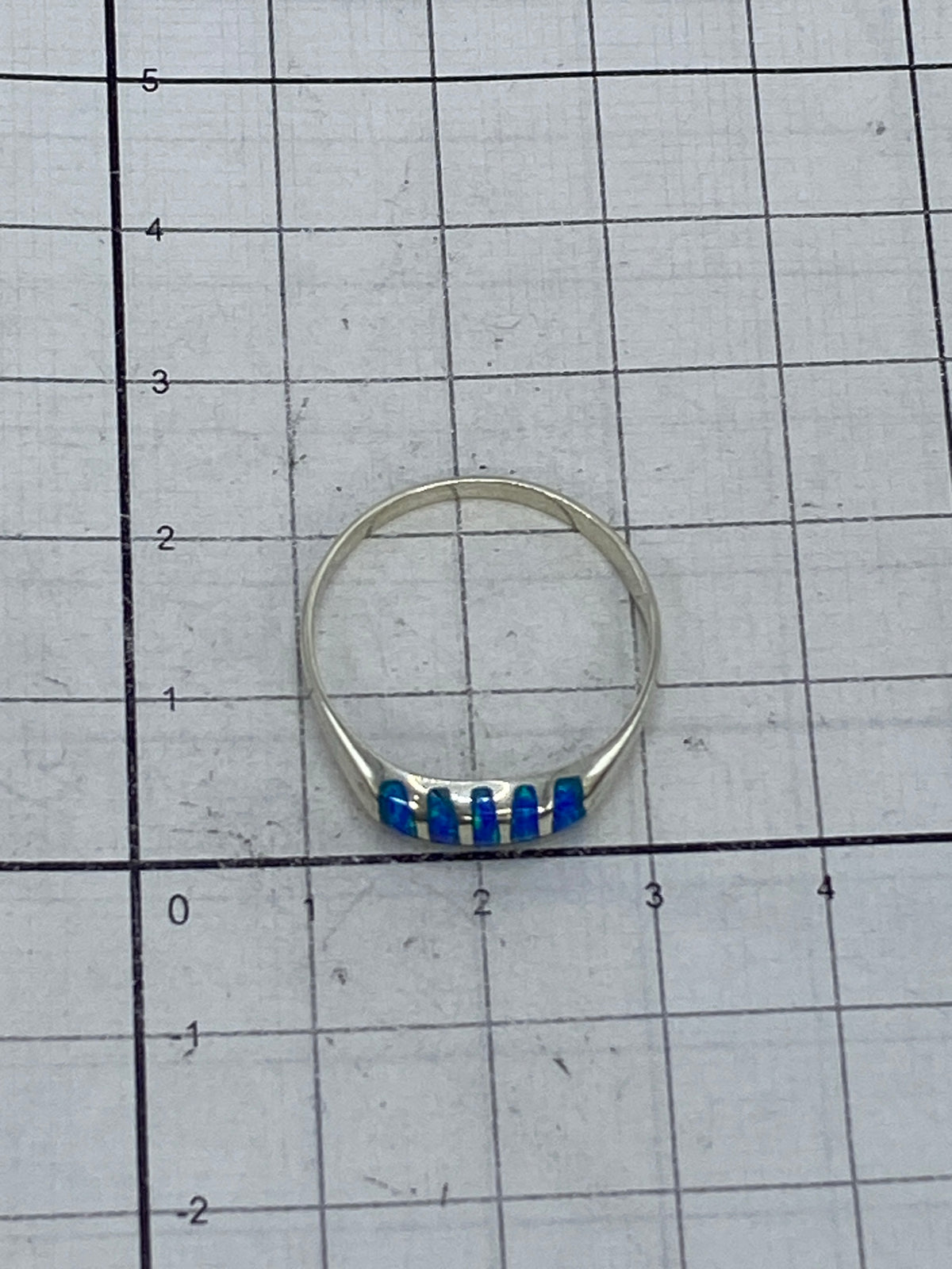 Anillo de plata ligero sobre fondo blanco con ópalo de fuego visible