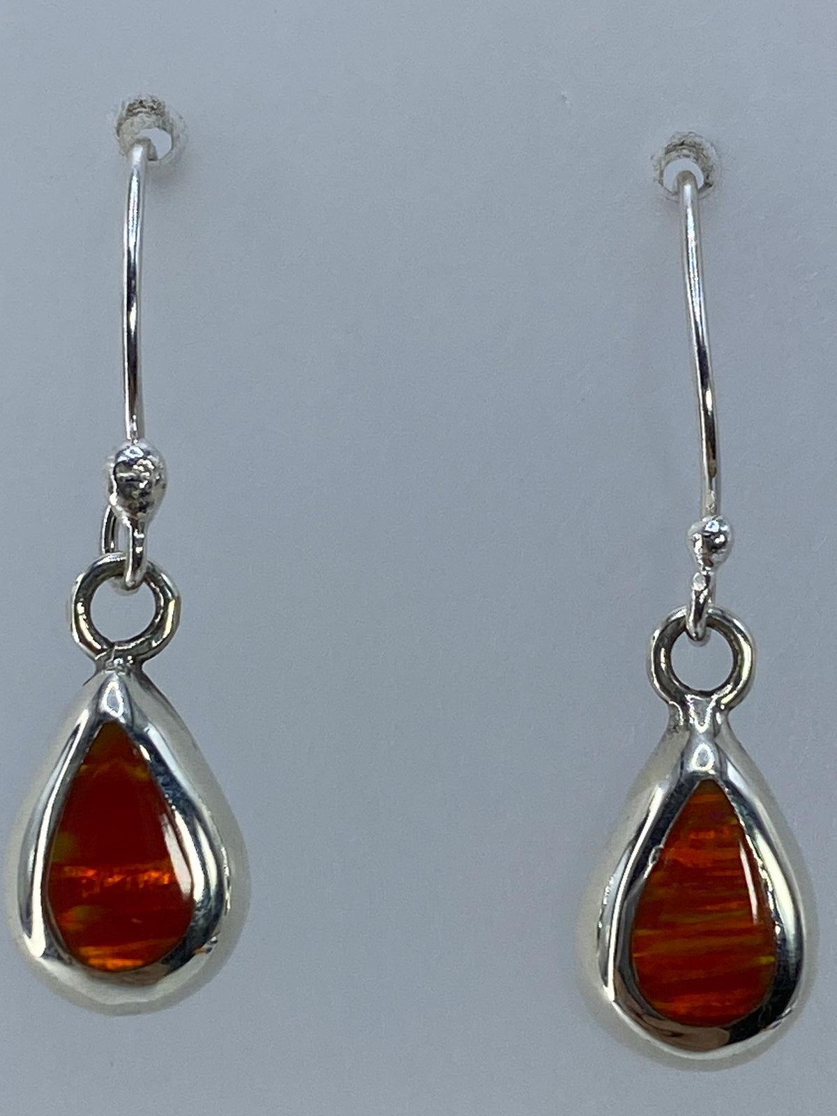 Aretes de plata con piedra ópalo sobre regla de centímetros mostrando 3 cm de largo