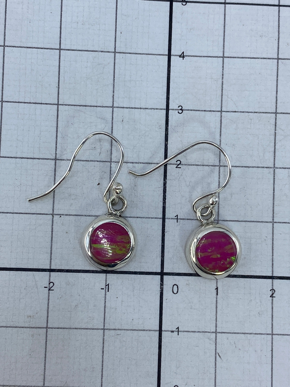 Aretes con ópalo de fuego en la mano, luciendo el color verde bosque
