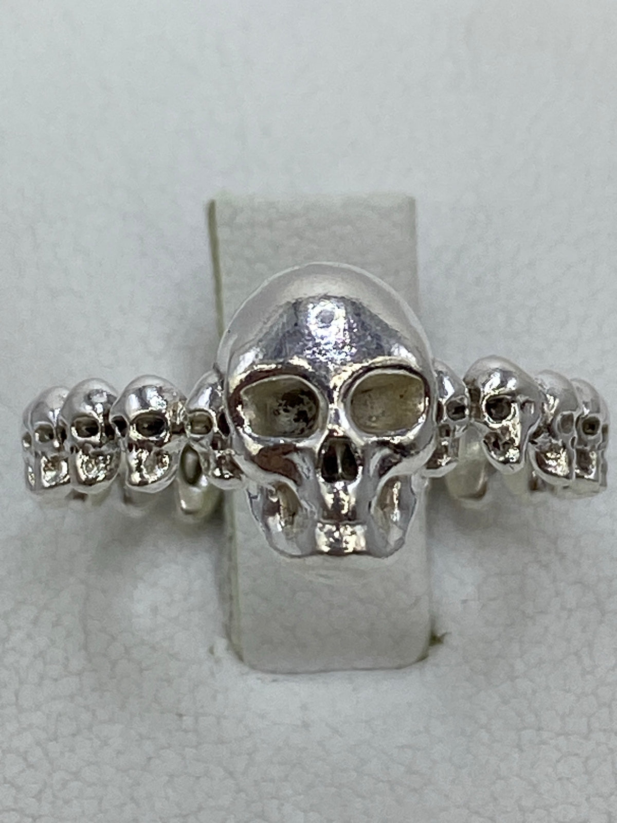 Anillo de plata 950 con calavera central rodeada de calaveras miniatura en la mano de una mujer