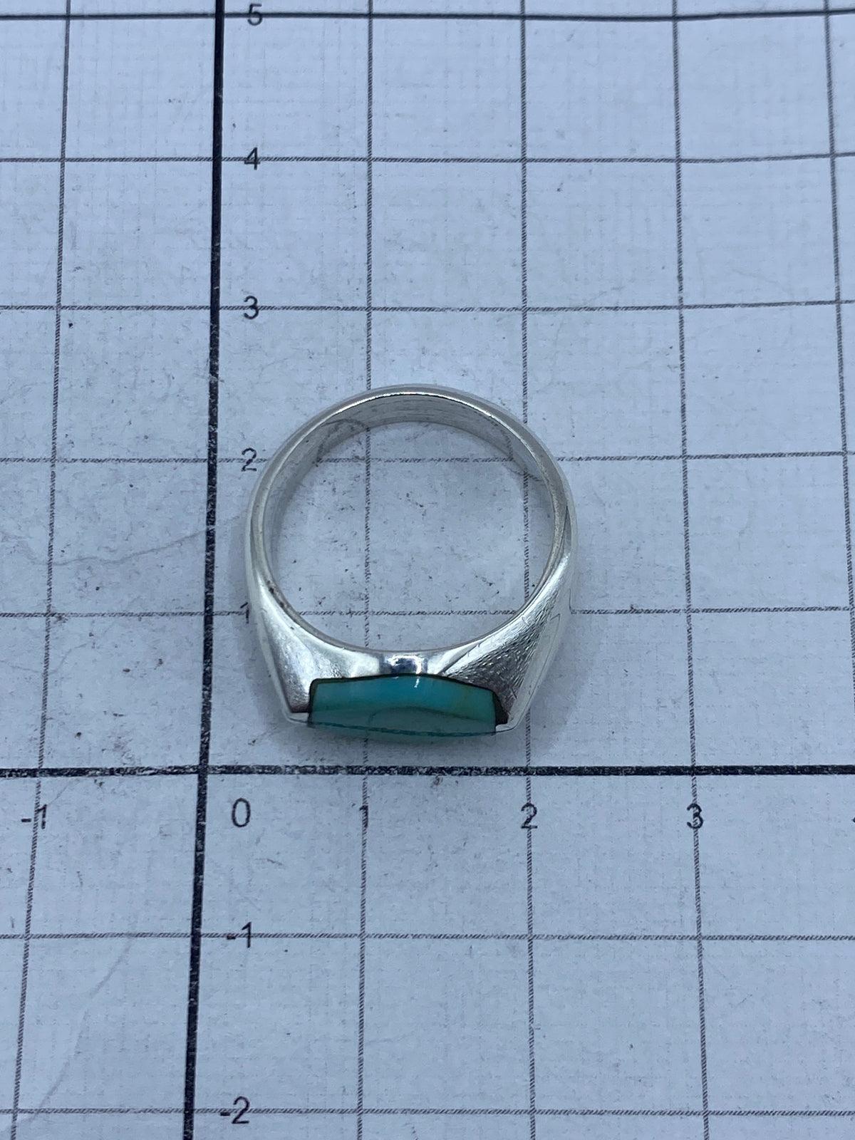 Anillo puesto en dedo mostrando el brillo natural de la turquesa y el acabado satinado de la plata