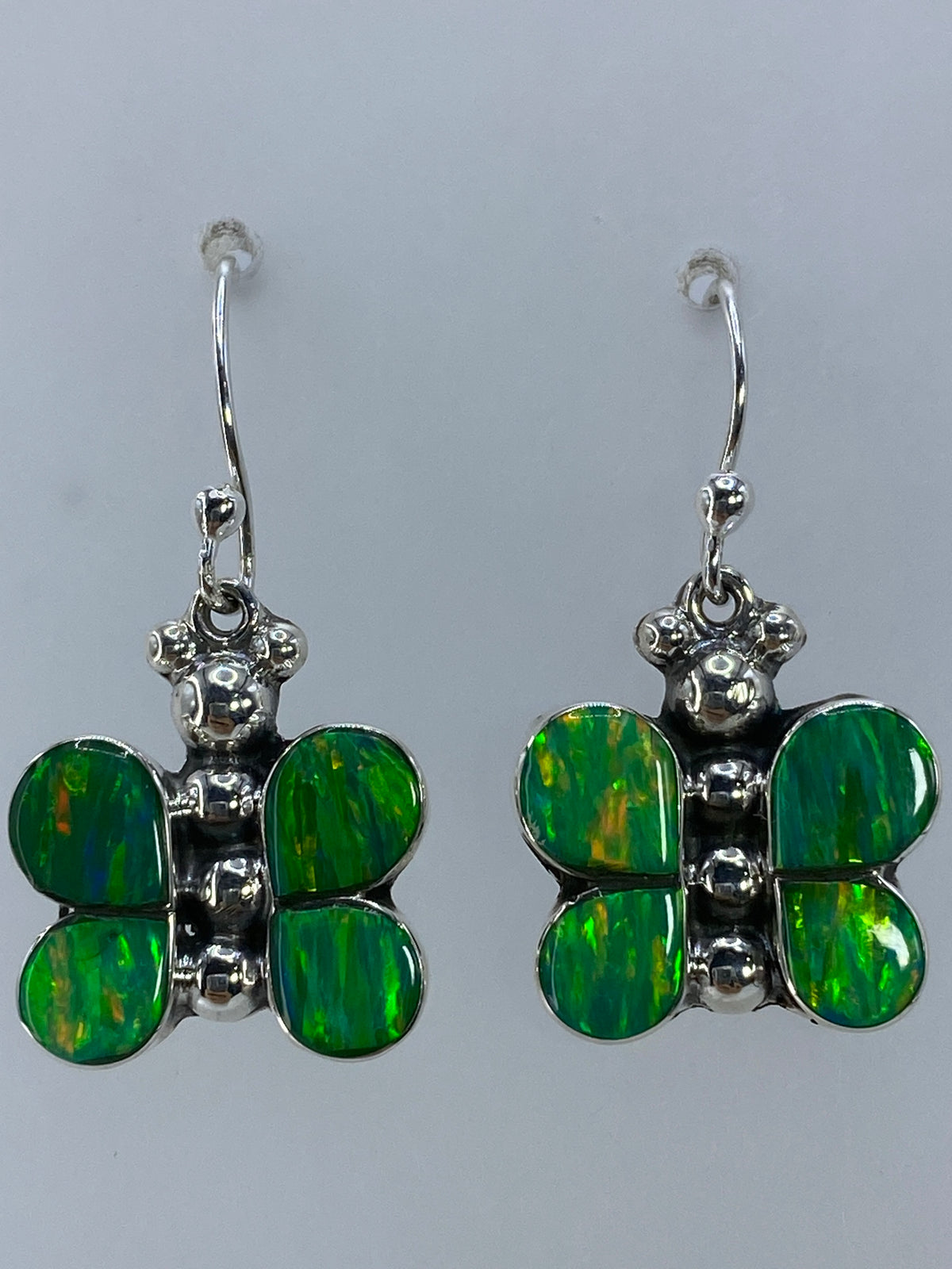 Aretes en la mano mostrando el brillo vivo del ópalo verde limón bajo la luz