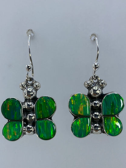 Aretes en la mano mostrando el brillo vivo del ópalo verde limón bajo la luz