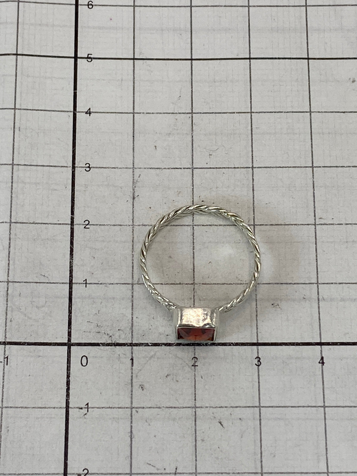 Anillo sobre fondo blanco mostrando el Quinto 925 y la piedra roja