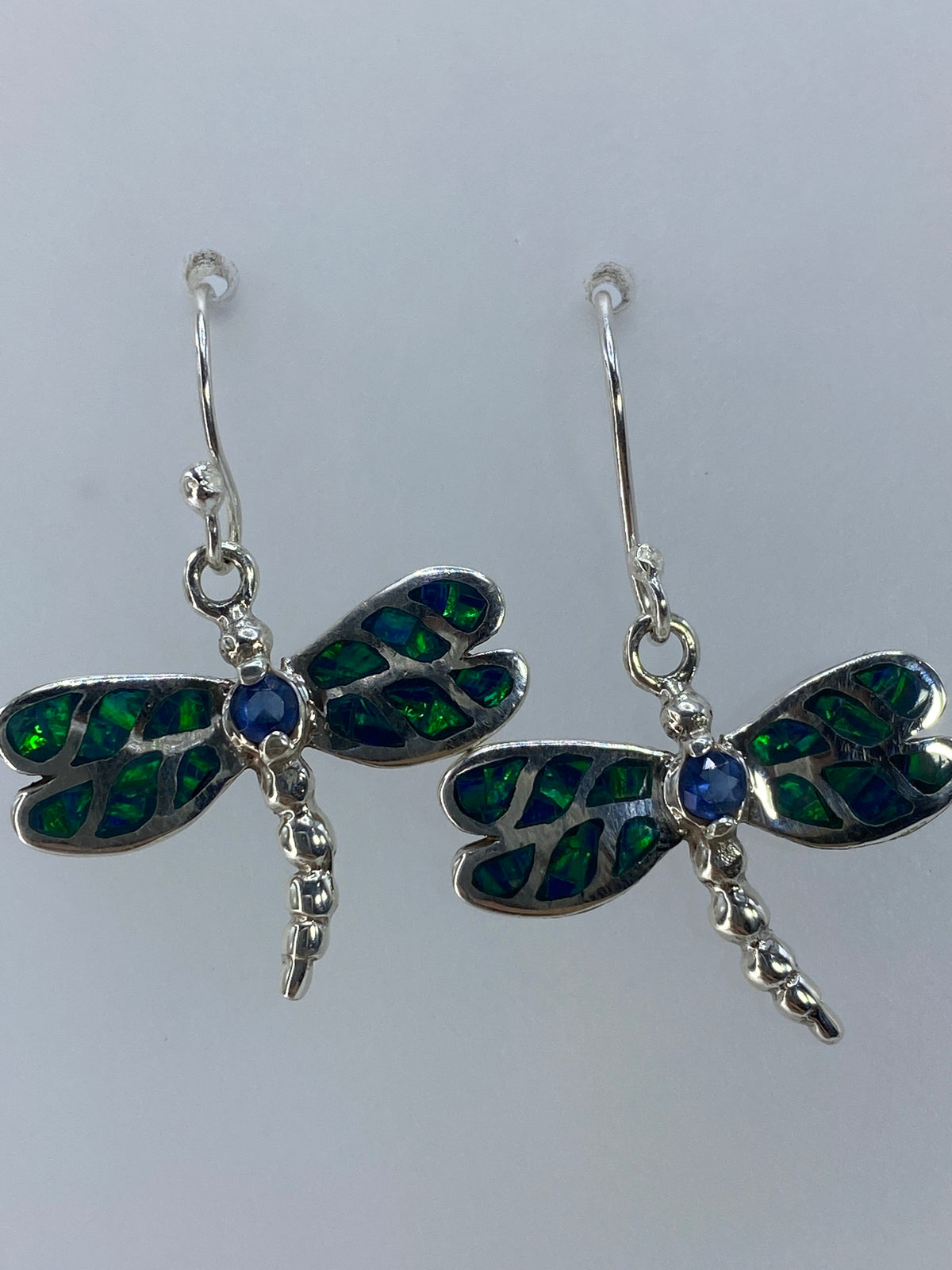 Detalle de los aretes mostrando la incrustación artesanal de piedras y el color verde y azul
