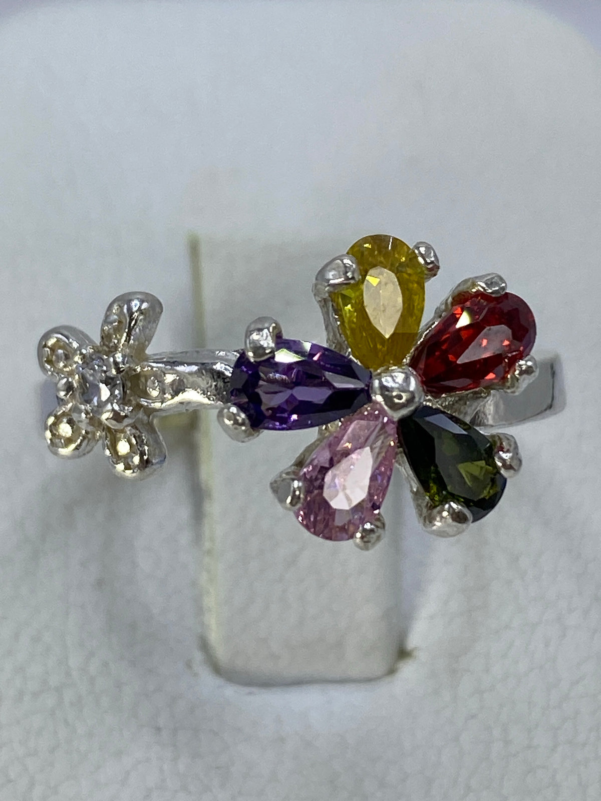 Anillo floral puesto en la mano mostrando el brillo de las cinco piedras de colores