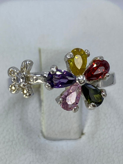 Anillo floral puesto en la mano mostrando el brillo de las cinco piedras de colores