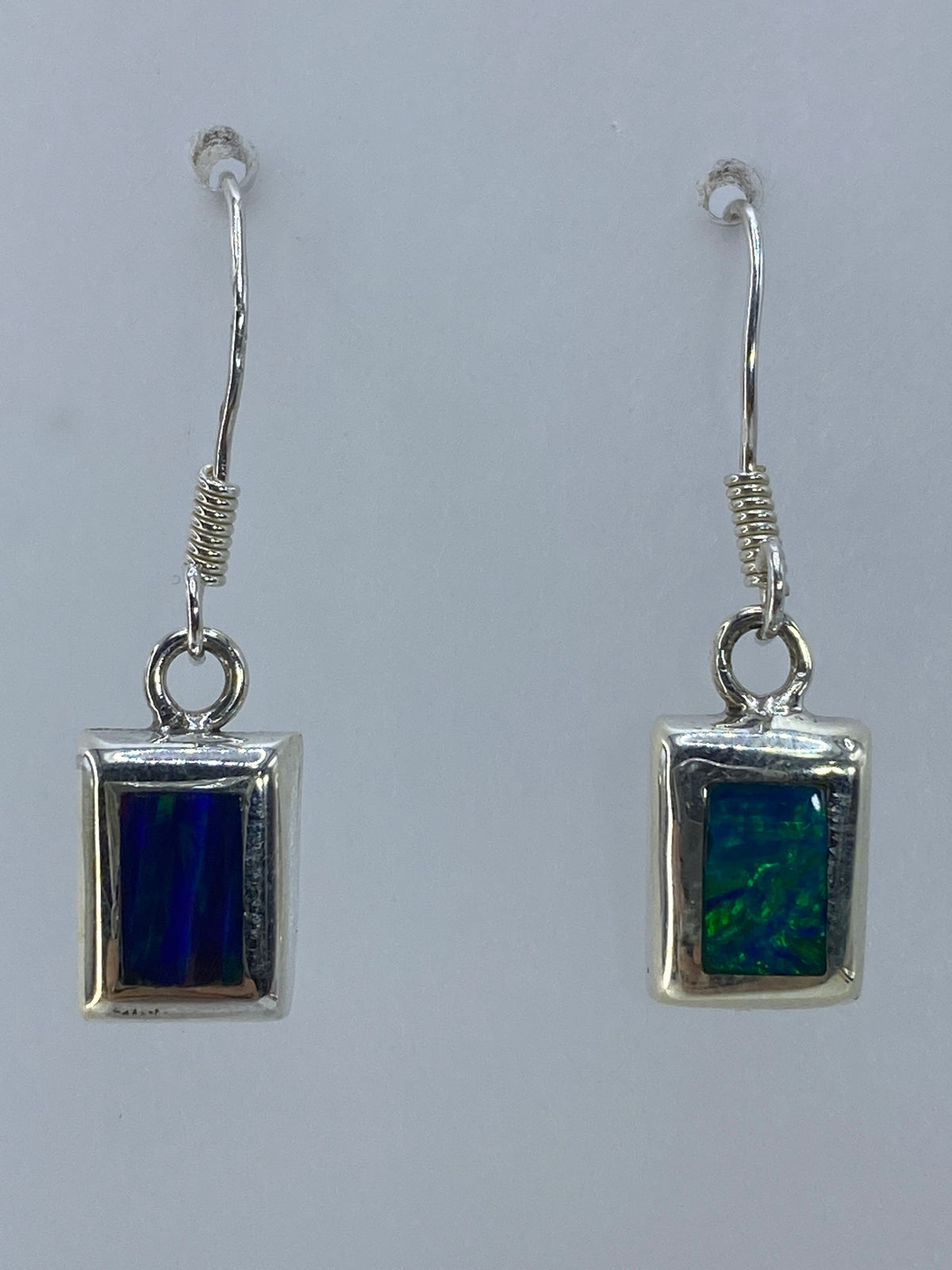 Aretes de plata con ópalo de fuego multicolor en tonos naranjas y verdes colgando en par