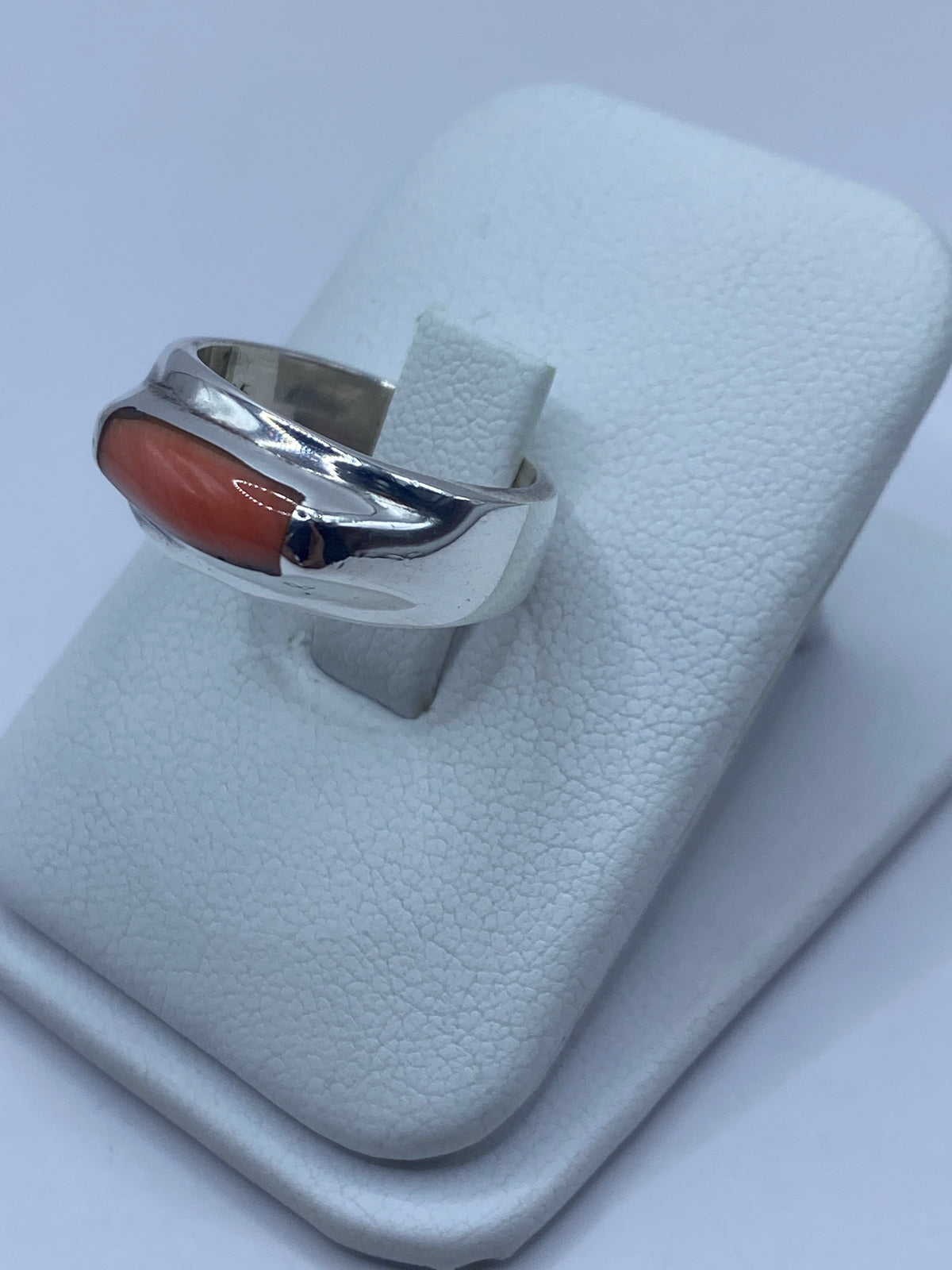 Detalle lateral del anillo mostrando el engaste a mano del coral en plata