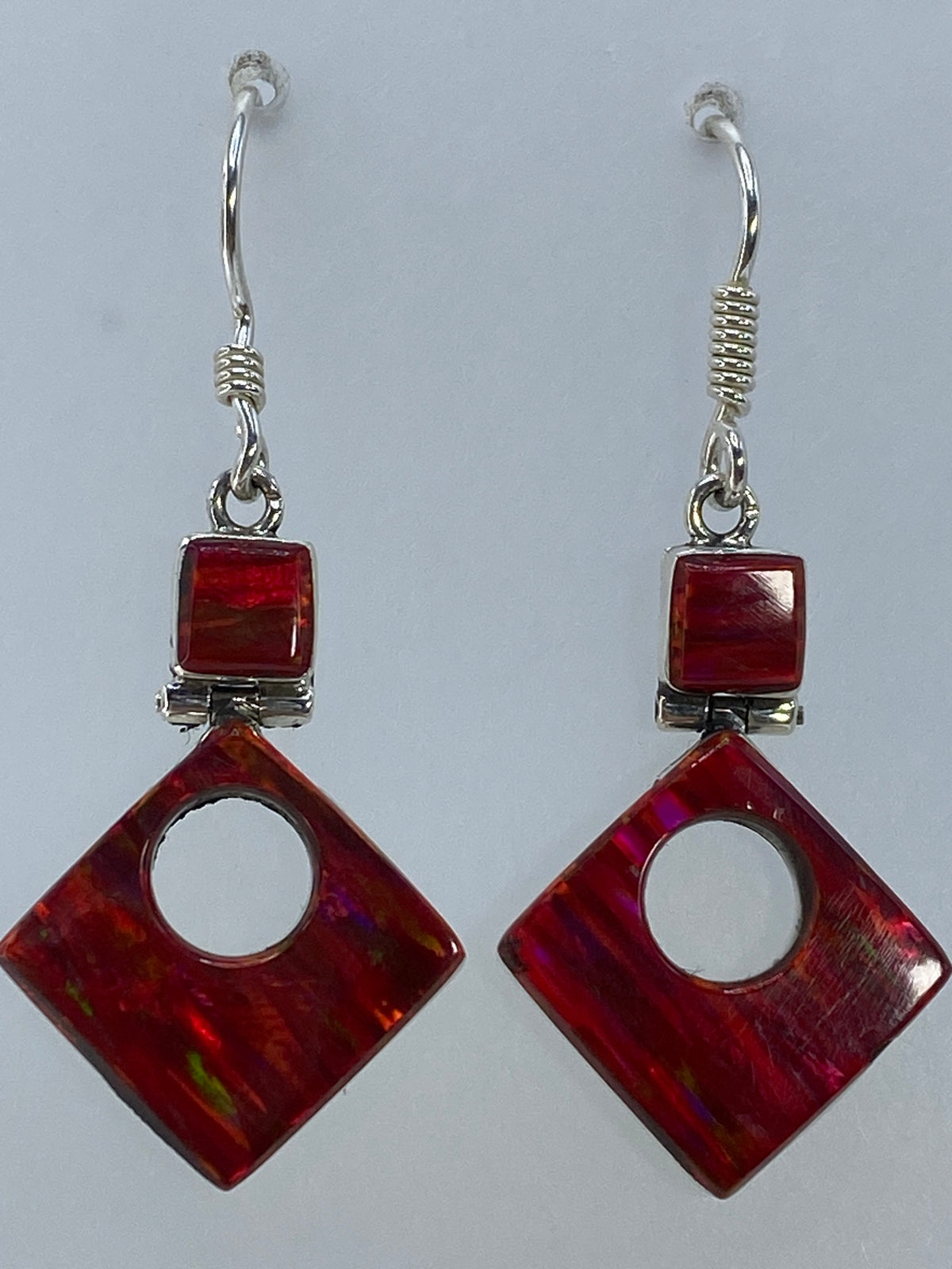 Par de aretes de plata 950 vistos de frente, mostrando la variación de color en la piedra