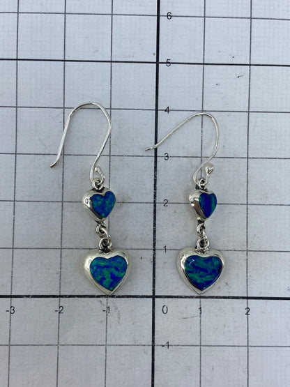 Aretes puestos en oreja, mostrando la proporción de 4 cm y el juego de luz del ópalo