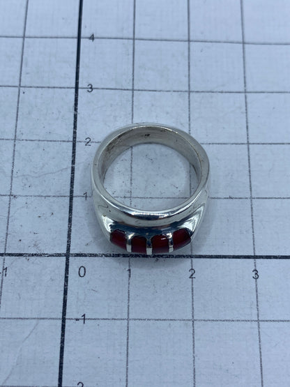 Anillo de plata con coral rojo puesto en el dedo, mostrando el brillo y el color cálido