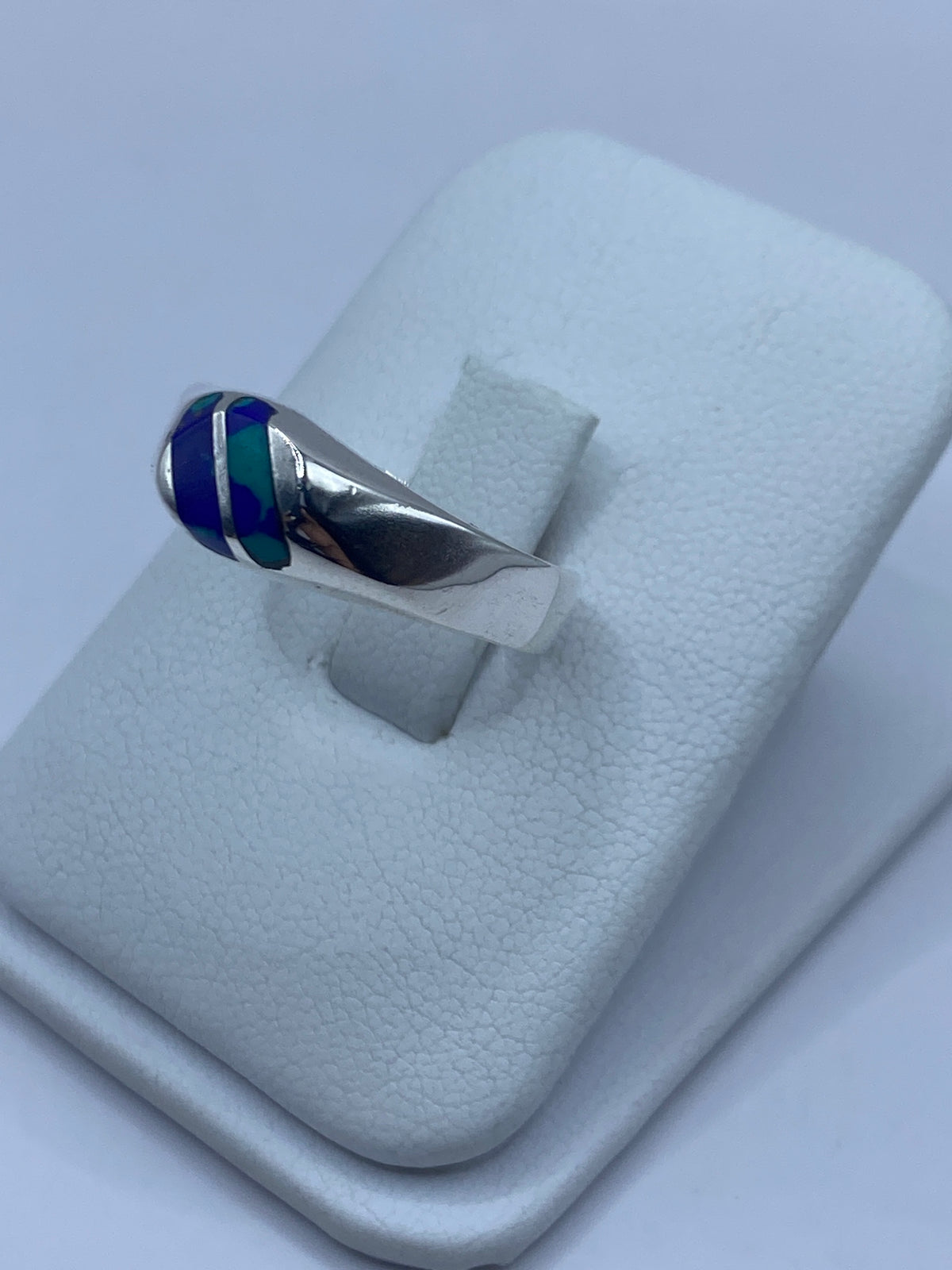 Detalle lateral del anillo mostrando el engaste a mano y la piedra azul