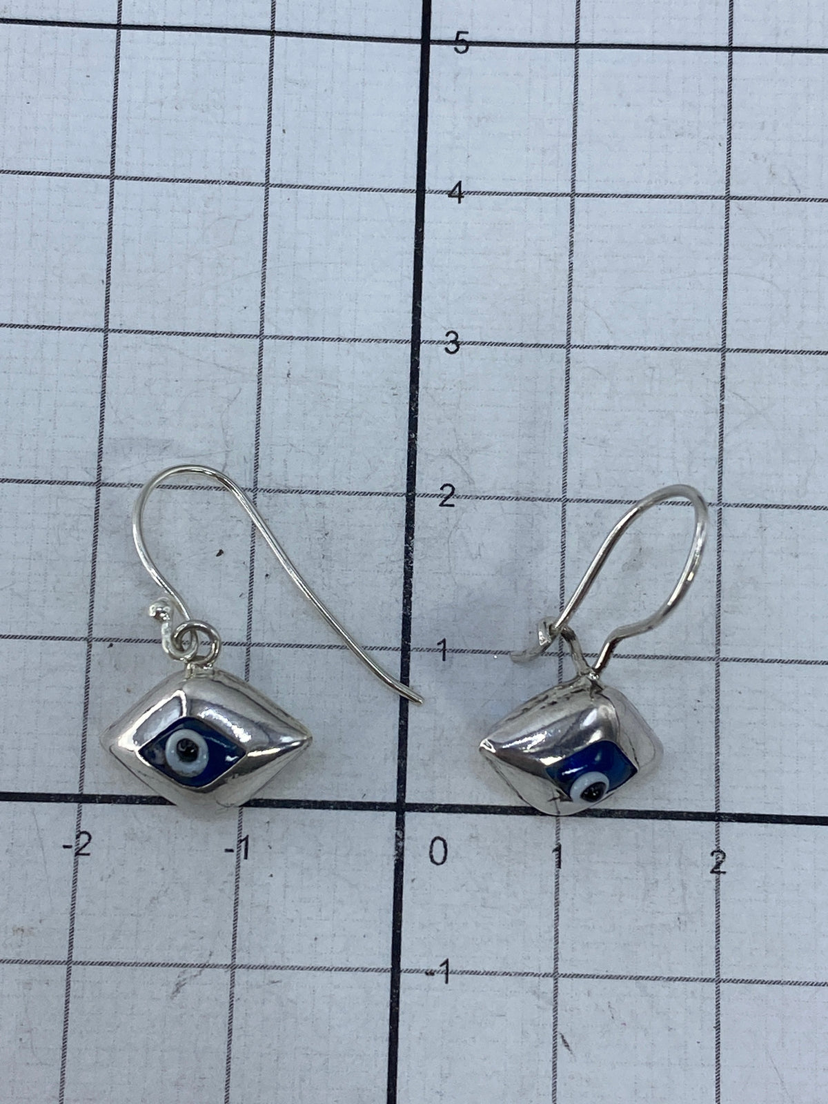 Aretes de plata junto a báscula mostrando peso total de 2.16 gramos