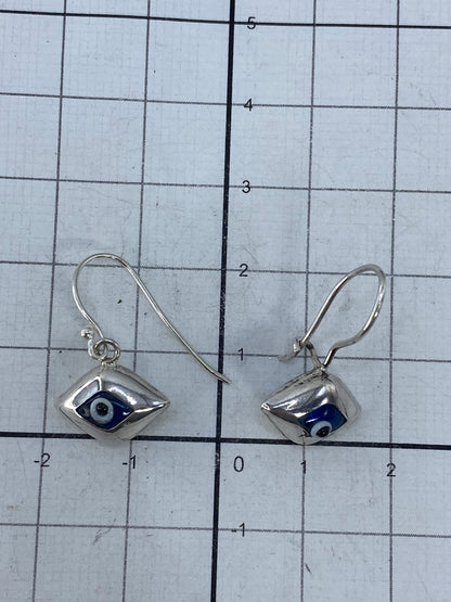 Aretes de plata junto a báscula mostrando peso total de 2.16 gramos